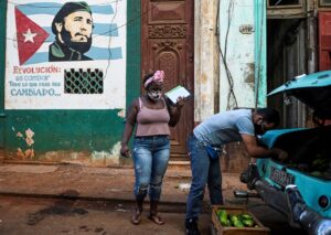Cubans unload avocados for sale, next to a mural showing the late Cuban leader Fidel Castro. FILE PHOTO AFP/ YAMIL LAGE