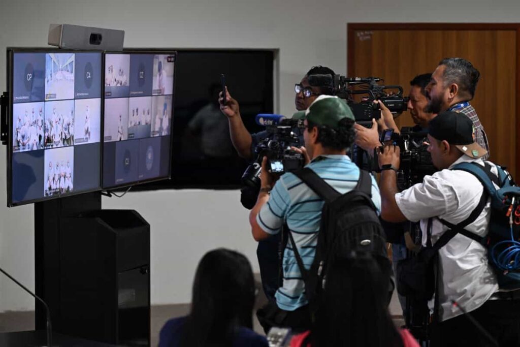 Journalists record and picture monitors broadcasting the mass hearing against alleged leaders of the Mara Salvatrucha (MS-13) at the Judicial Center Against Organized Crime in Soyapango, El Salvador, on April 20, 2026.