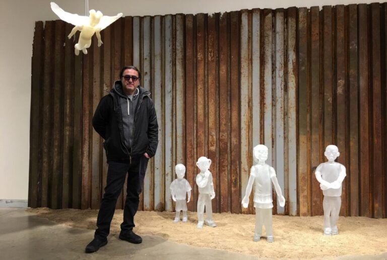 The glass sculptor Jaime Guerrero in a representation of the migratory drama on the wall that divides the United States and Mexico. PHOTO: COURTESY OF JAIME GUERRERO