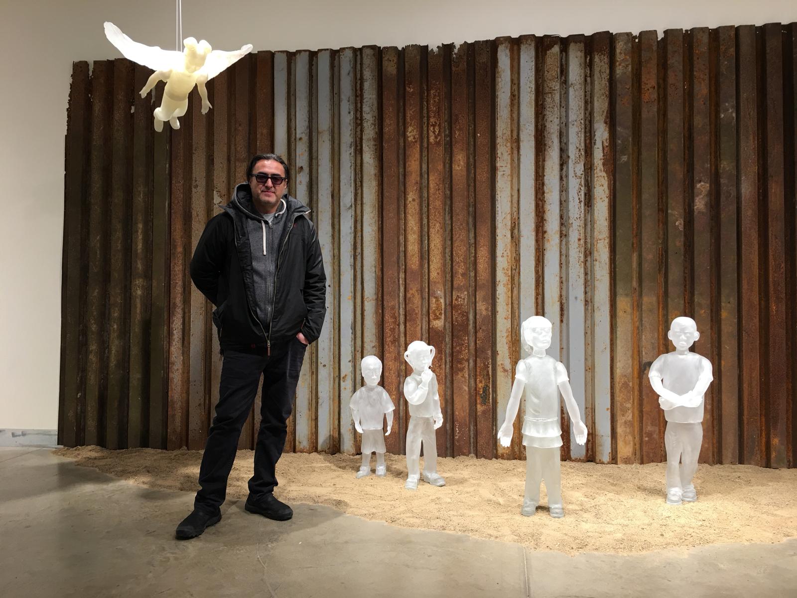 The glass sculptor Jaime Guerrero in a representation of the migratory drama on the wall that divides the United States and Mexico. PHOTO: COURTESY OF JAIME GUERRERO