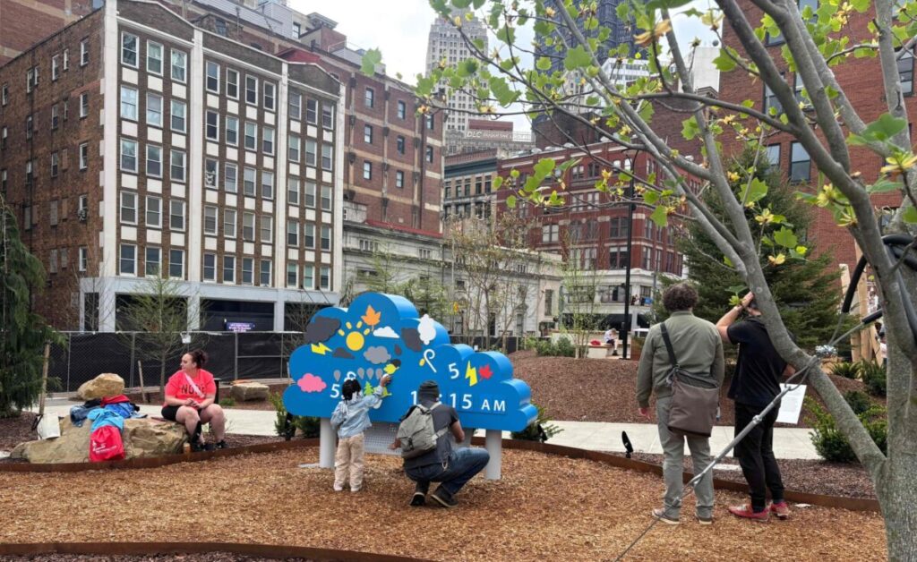 One of the artists who contributed his work to the inauguration of Arts Landing shares the content of the piece with a young girl. PHOTO: PITTSBURGH GLOBAL NEWS / FREDDY POTOY